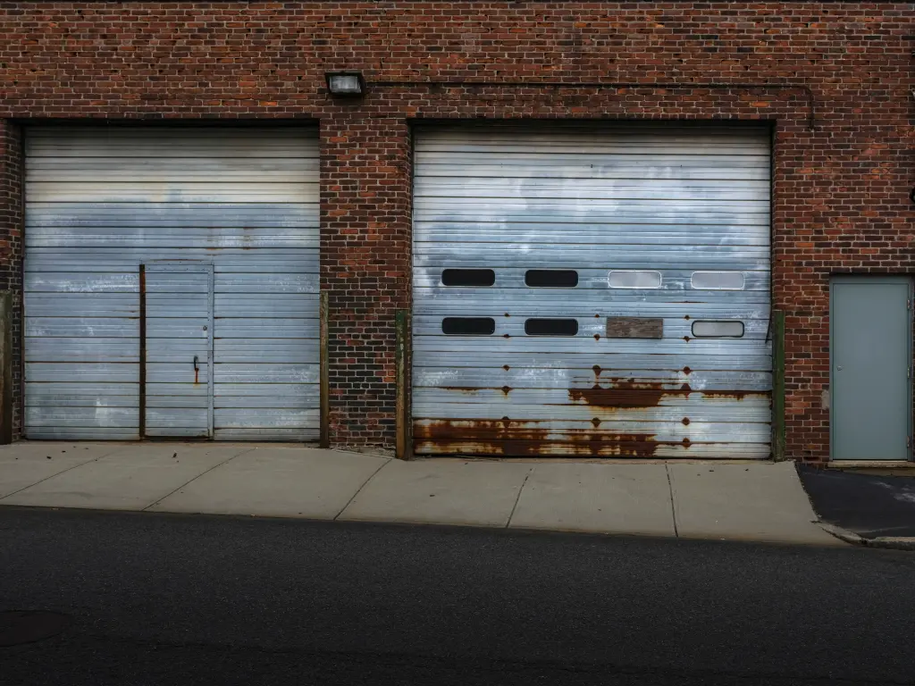 A homeowner applying a protective coating to a garage door to prevent rust formation